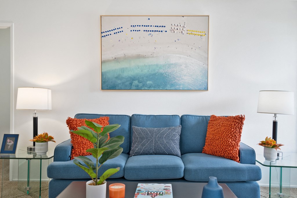 a living room with a blue couch and a painting on the wall