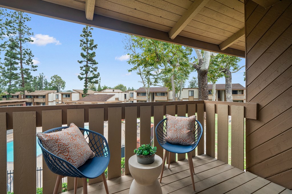 a balcony with two chairs and a view of a pool and trees