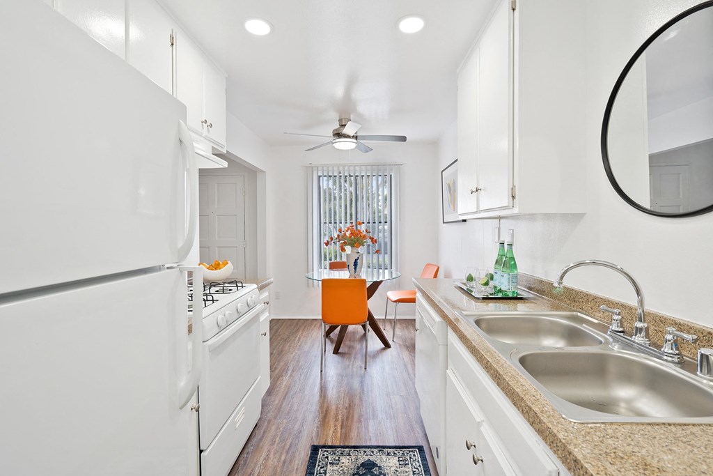 a kitchen with white appliances and counters and a table with a chair