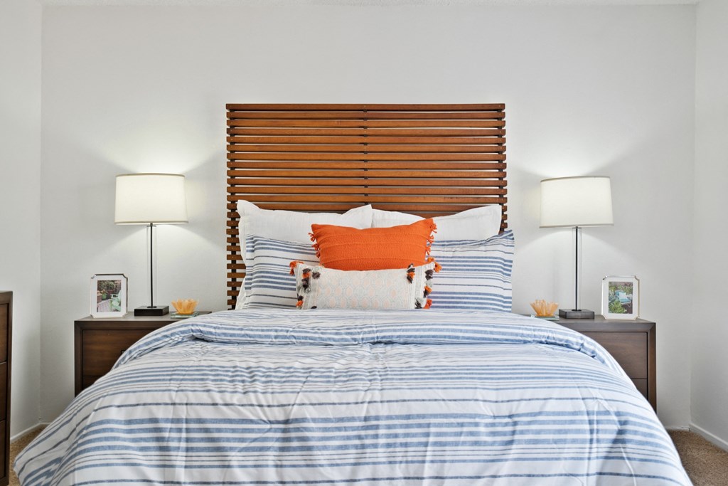 a bedroom with a bed with blue and white bedding and an orange pillow