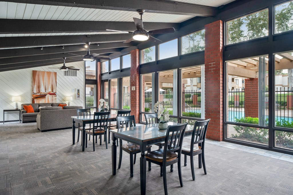 a dining area with a table and chairs and large windows