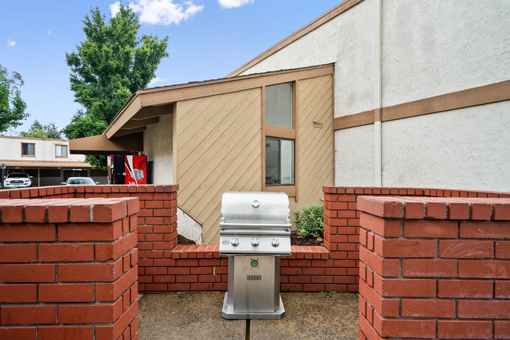 a silver grill in front of a brick fence and a house