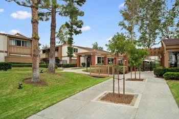 an exterior view of an apartment building with trees and a sidewalk