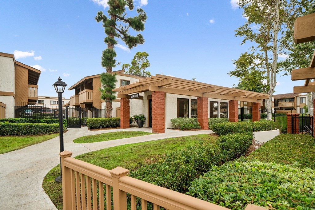 a courtyard with a sidewalk and a building with brick pillars