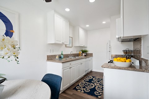 a kitchen with white cabinetry and a counter top with a bowl of fruit