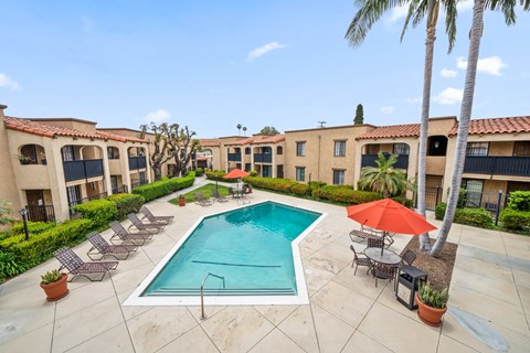 a swimming pool with lounge chairs and umbrellas in front of a building