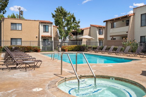 A swimming pool surrounded by lounge chairs and buildings.