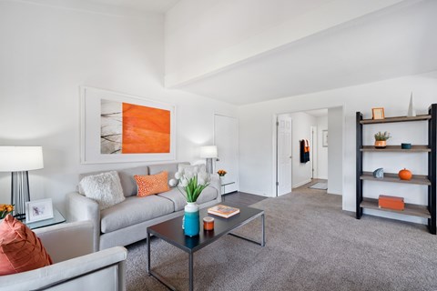 A living room with a grey couch, a coffee table, and a painting on the wall.