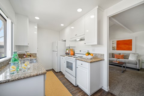 A kitchen with white cabinets and a granite countertop.