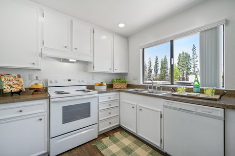A kitchen with white cabinets and appliances.