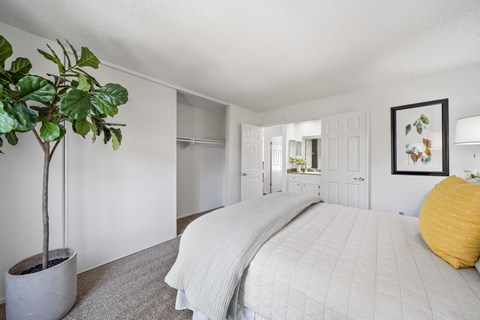 a white bedroom with a white bed and a potted plant