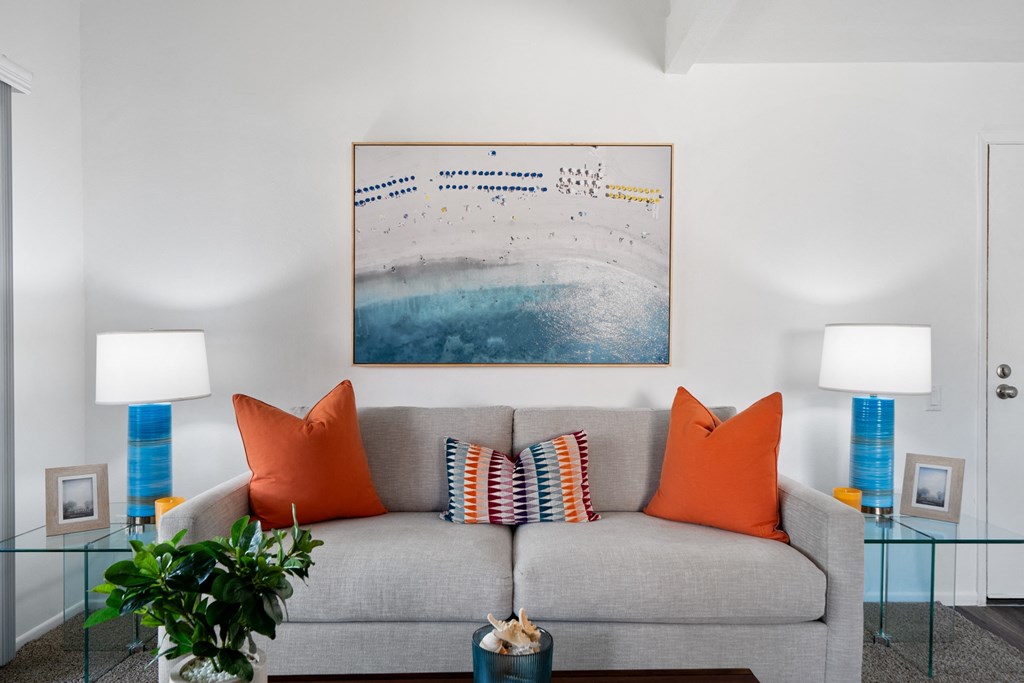 a living room with a gray couch and orange pillows