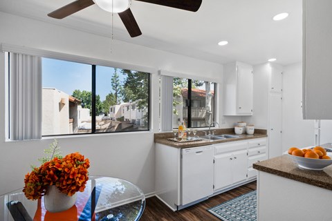 a kitchen with a large window and a table with a bowl of fruit