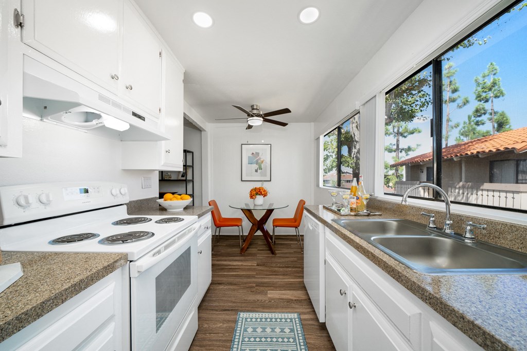 a kitchen with white cabinets and a sink and a window