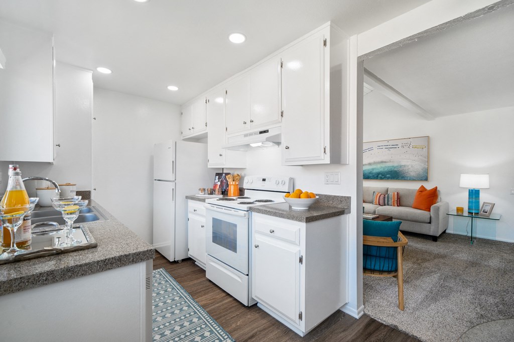 a kitchen with white cabinets and a counter top and a white refrigerator