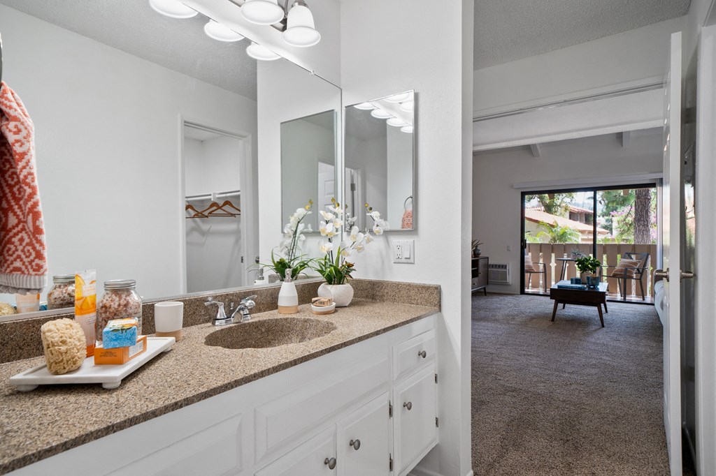 a bathroom with a sink and a mirror and a living room
