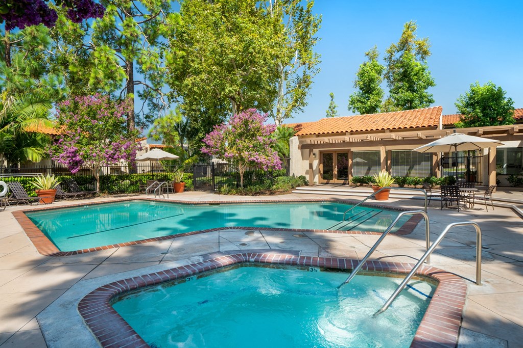 a swimming pool with a hot tub and a resort style building in the background