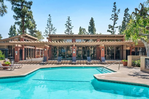 A large swimming pool in front of a building with a covered patio area.