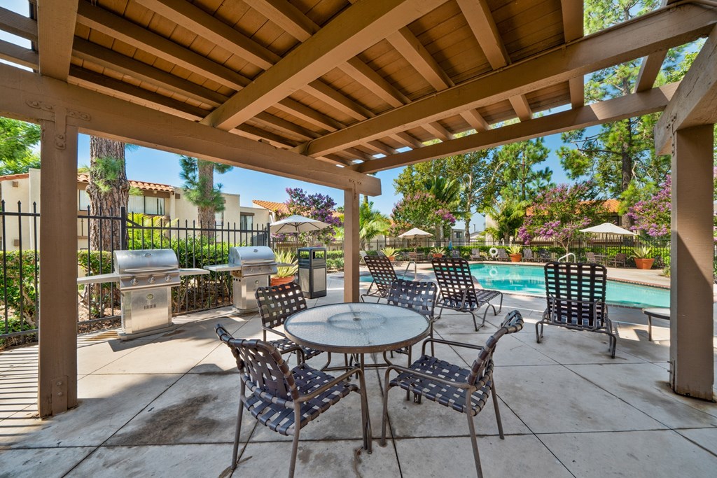 a patio with a table and chairs next to a swimming pool