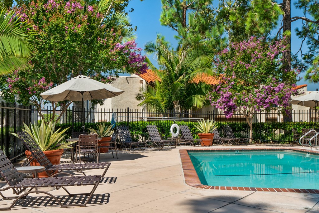 a swimming pool with chairs and umbrellas near a resort style pool