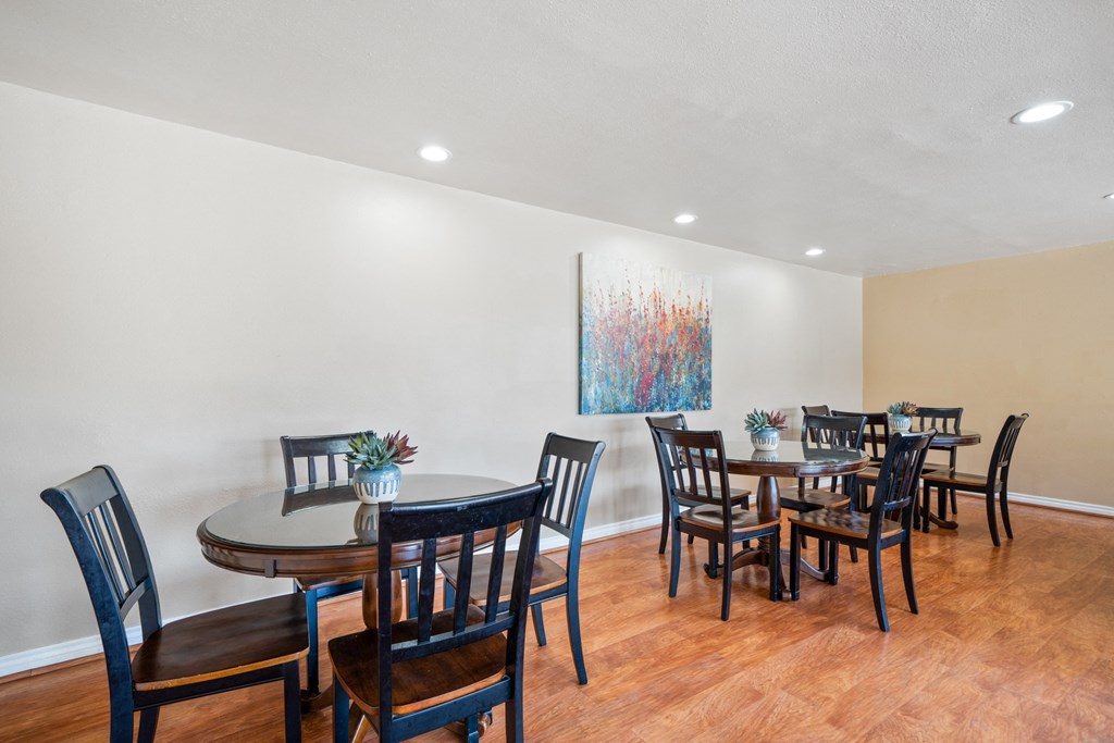 a dining room with tables and chairs and a painting on the wall