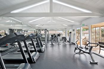 a gym with a lot of cardio equipment and chairs