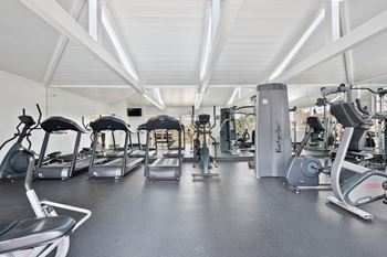 a gym with cardio equipment and weights on the floor
