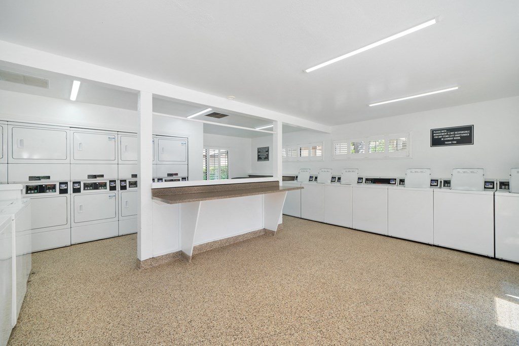 a laundry room with a counter and white cabinets