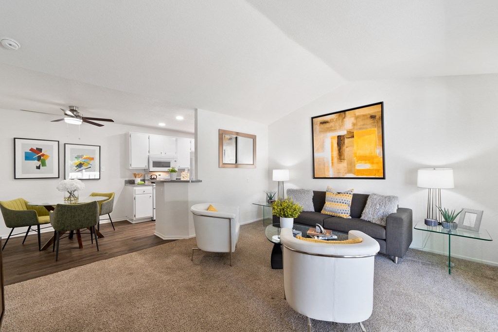 a living room with a couch and a coffee table and a kitchen in the background