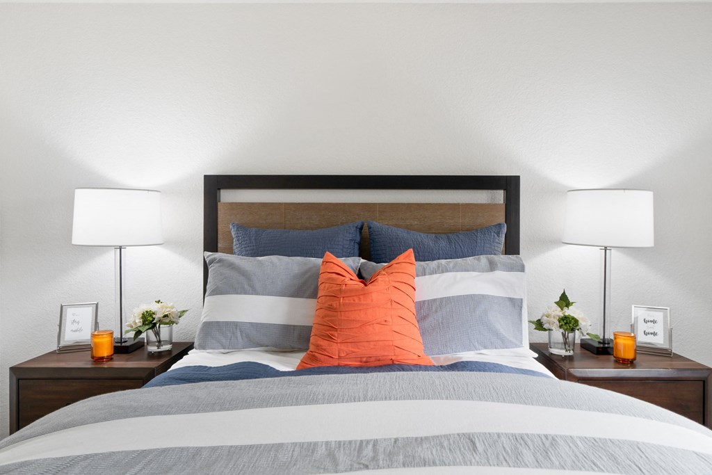 a bedroom with a bed with blue and orange pillows