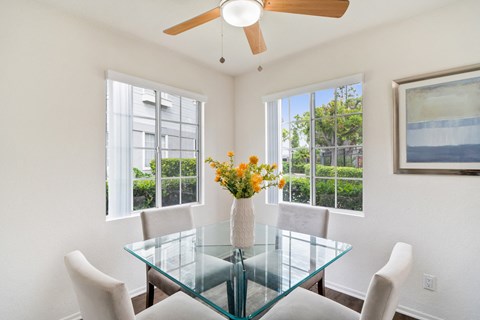 a dining room with a glass table and chairs and windows