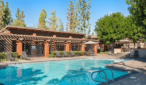 A swimming pool in front of a building with a red tiled roof.