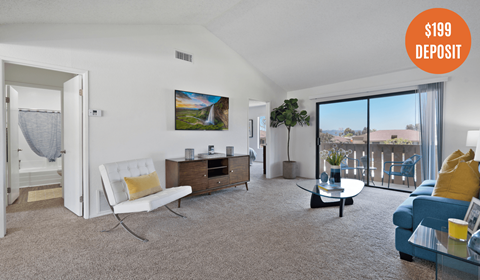 A living room with a white chair, a blue couch, and a painting on the wall.