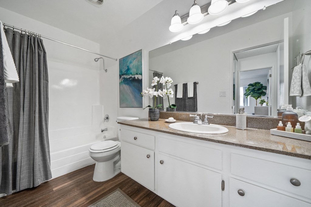 a bathroom with white cabinets and a gray shower curtain