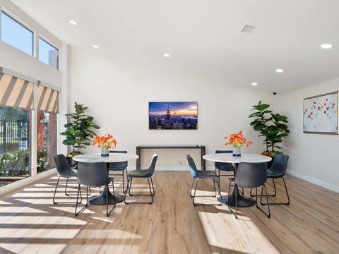 a room with tables and chairs and a large painting of a city on the wall
