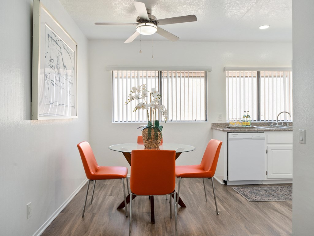 a dining area with a table and chairs and a kitchen in the background