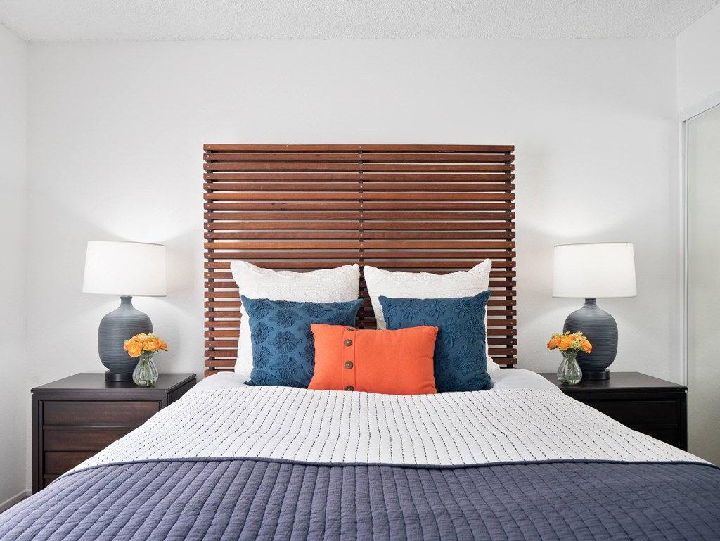 a bedroom with a bed with blue and orange pillows