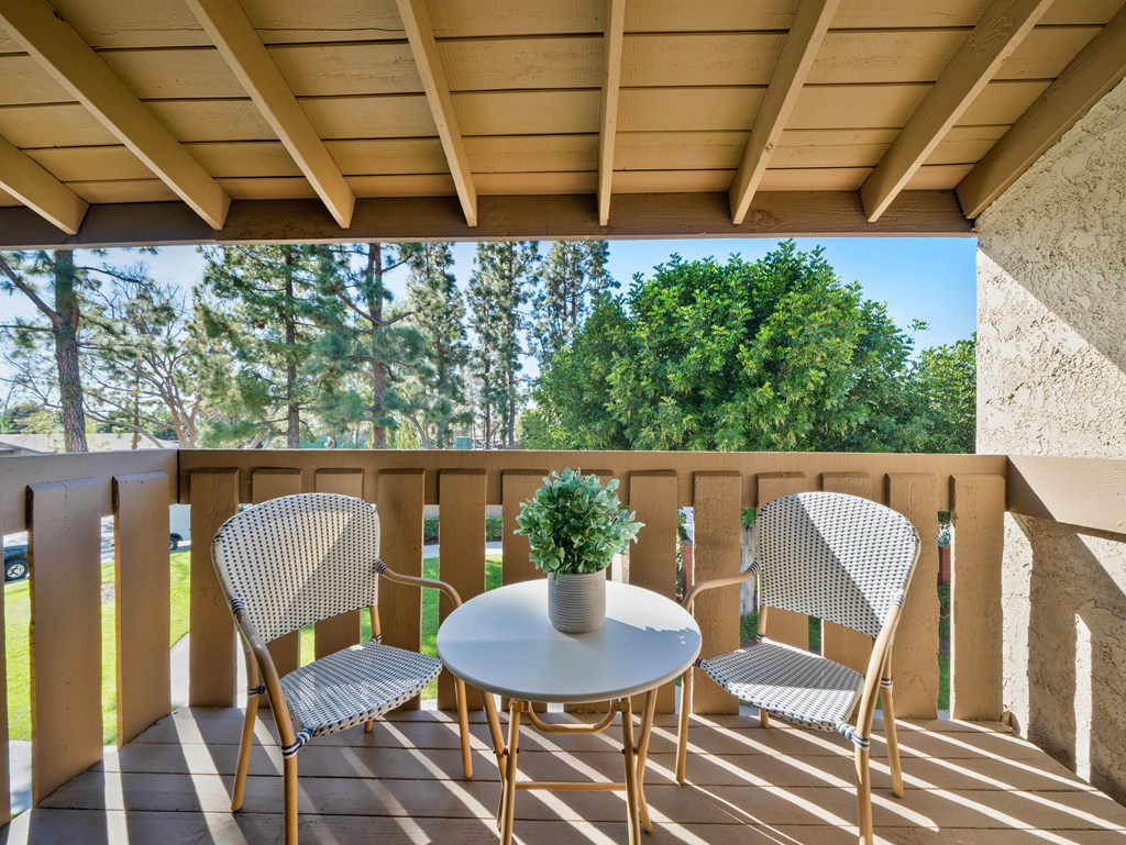 a patio with two chairs and a table with a plant on it
