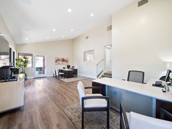 an office with a desk and chairs with a doorway into a room in the background