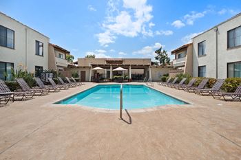 a swimming pool with lounge chairs and umbrellas in front of a building