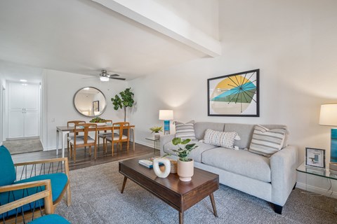 A living room with a grey couch, a wooden coffee table, and a painting on the wall.