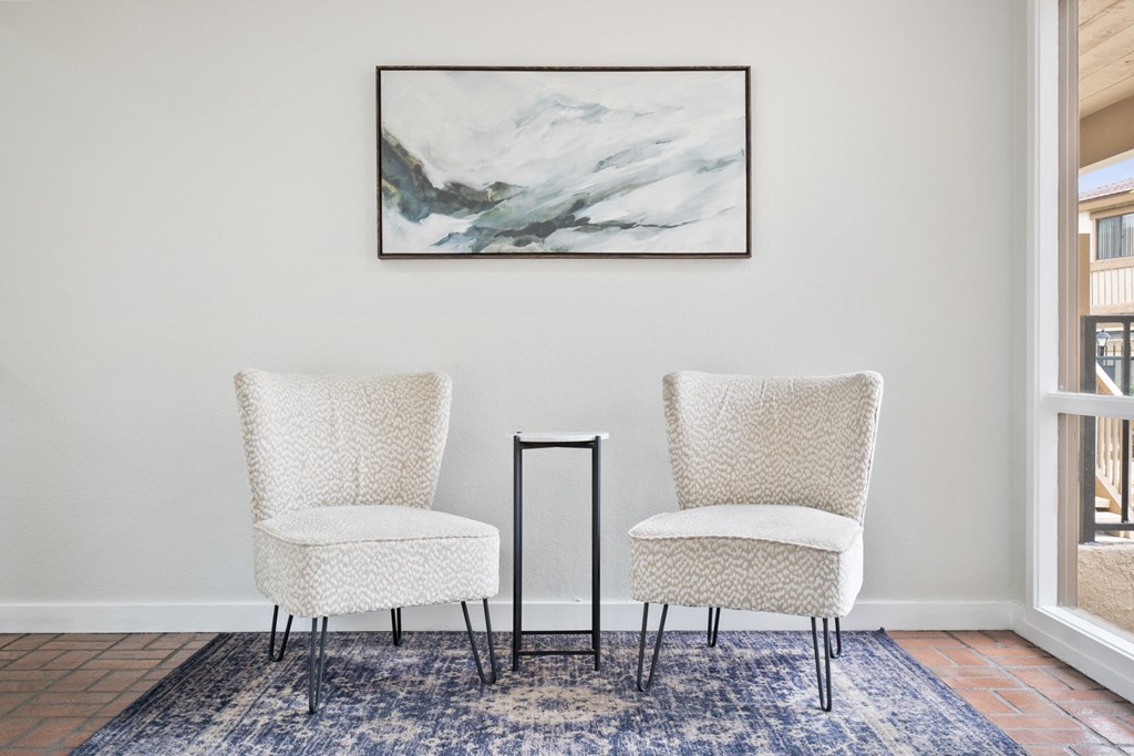 two chairs in a living room with a painting on the wall