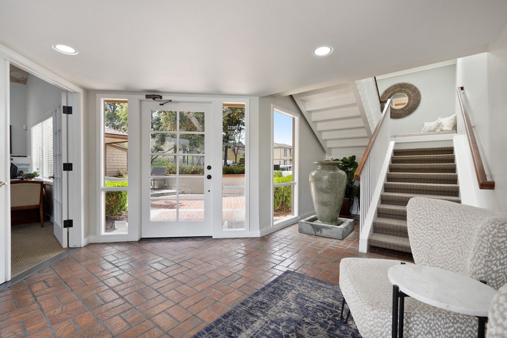 a living room with two chairs and a staircase with glass doors