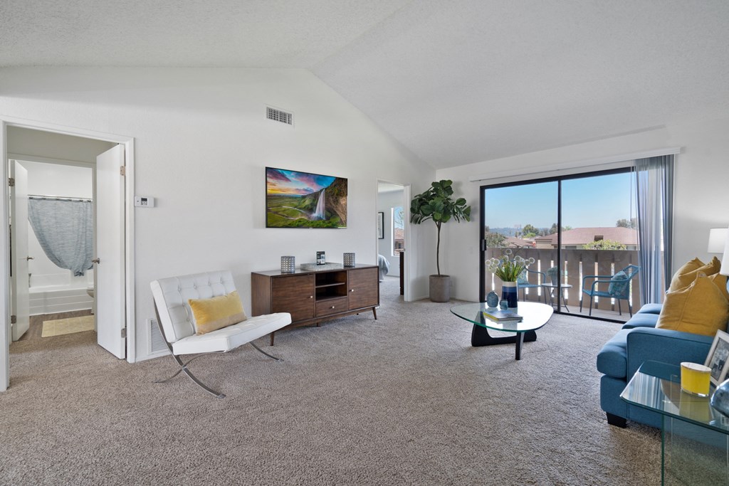a living room with a blue couch and a white chair and a sliding glass door