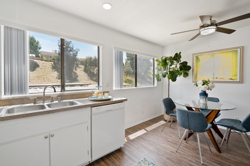 a kitchen with white cabinets and a dining room with a table and chairs