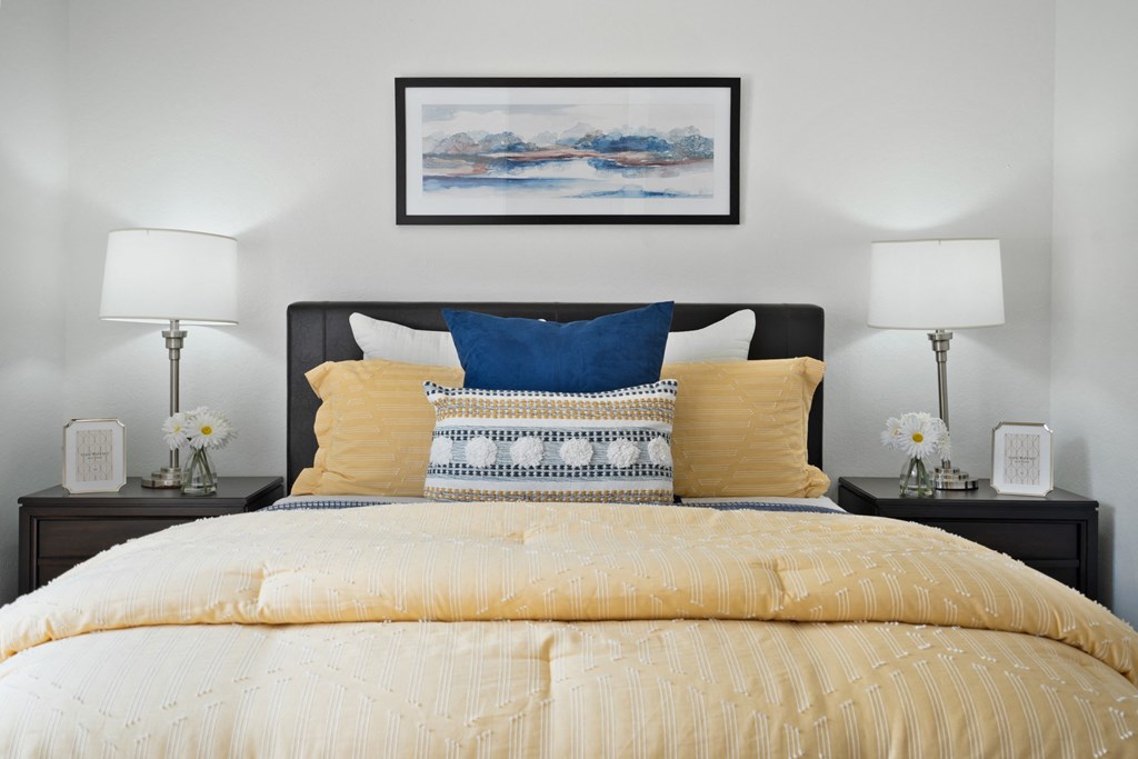 a bedroom with a bed with yellow and blue pillows