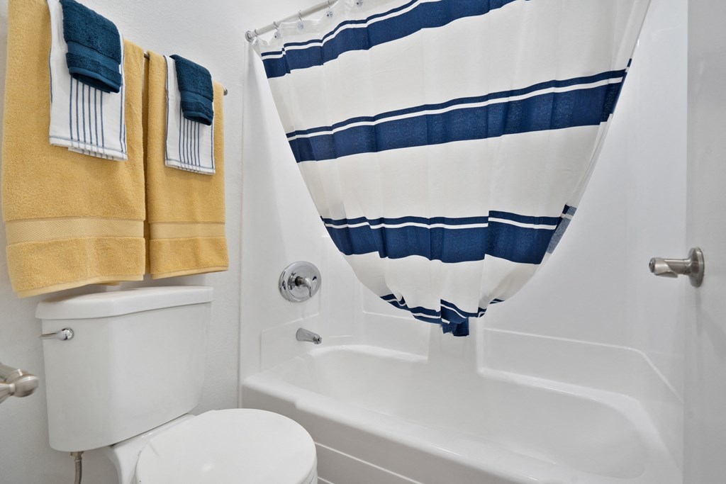 a bathroom with a shower curtain and a toilet and a tub