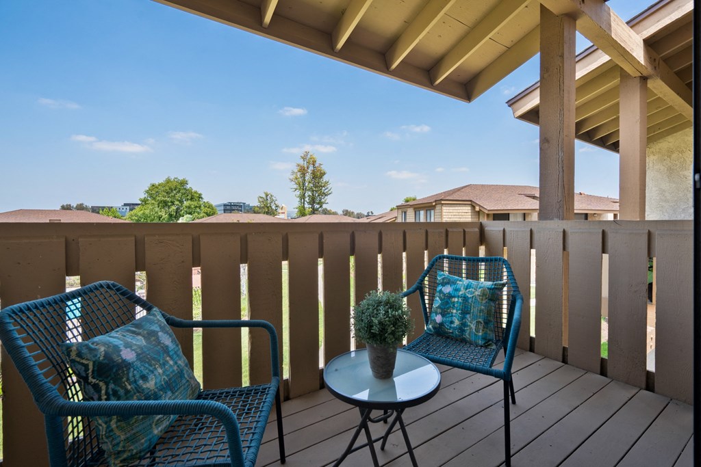 a patio with two chairs and a table on a deck