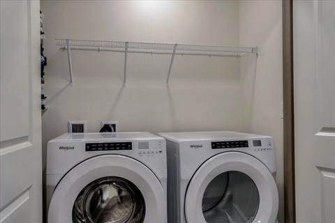 Two Whirlpool washing machines in a small laundry room.