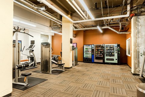 A gym with orange walls and a variety of equipment.
